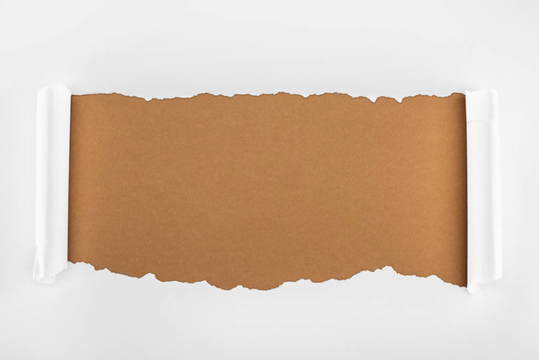zerrissenes weißes strukturiertes Papier mit Lockenrändern auf braunem Hintergrund  - Foto, Bild