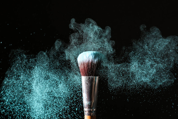 Makeup brush and burst of eyeshadows on dark background - Foto, afbeelding