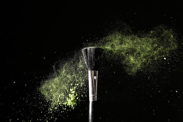Makeup brush and burst of eyeshadows on dark background - Foto, Bild