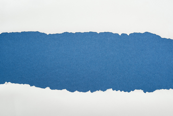 濃い青色の背景にコピースペースがある不規則な白いテクスチャの用紙  - 写真・画像