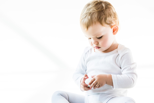adorable niño con pelo rubio sosteniendo huevo de gallina aislado en blanco
 - Foto, Imagen