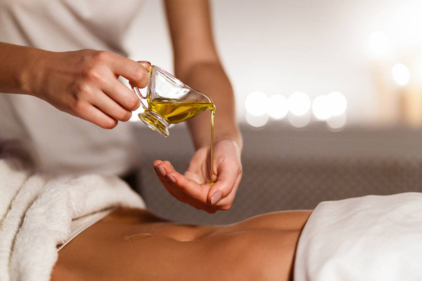 Masseur pouring oil on hand, preparing for massage - Foto, imagen