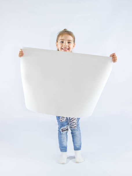 little girl holding a sheet of white paper - Fotó, kép