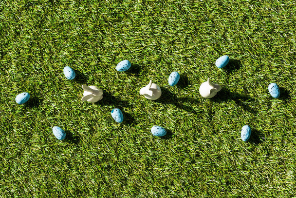 yeşil çim yüzeyinde Dekoratif tavşan ve mavi bıldırcın yumurtaları üst görünümü - Fotoğraf, Görsel