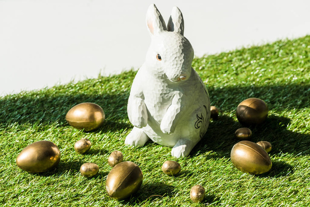decorative Easter rabbit end shiny golden eggs isolated on grey - 写真・画像