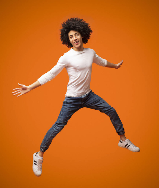 Vrolijke Afro-Amerikaanse Curly Guy springen in de lucht - Foto, afbeelding