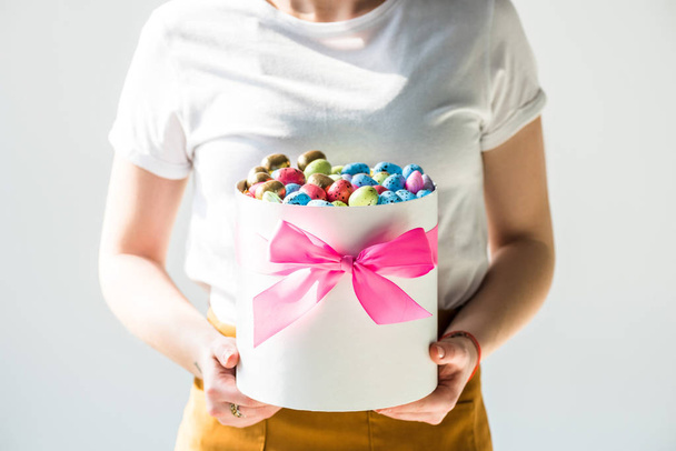 cropped view of woman holding round box full of colorful Easter eggs isolated on grey - Photo, Image