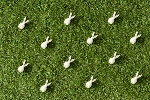 top view of decorative white bunnies on green grass surface  - Fotoğraf, Görsel