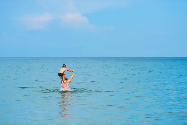 Un hombre con su hijo nadando en el mar. El descanso en la Crimea. Mar Negro. Un hombre arroja a un niño sobre el agua
. - Foto, imagen
