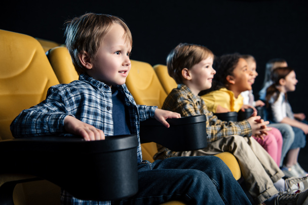 enfoque selectivo de amigos multiculturales sonrientes sentados en el cine y viendo películas
 - Foto, imagen