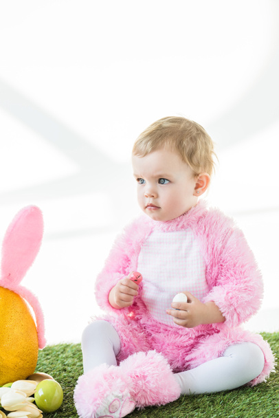 lindo niño en rosa traje esponjoso celebración de huevos de codorniz de colores aislados en blanco
 - Foto, Imagen