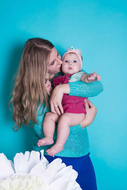 Onnellinen perhe. äiti ja lapsi tyttö leikkii, suudella ja halata sinisellä taustalla
 - Valokuva, kuva