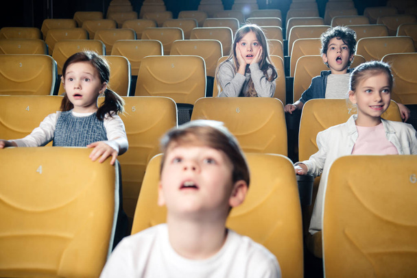 surprised multicultural friends watching movie in cinema together - Foto, Bild