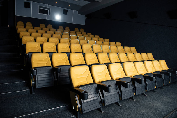dark cinema hall with comfortable empty seats with cup holders - Foto, Imagen