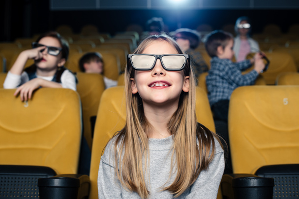 foyer sélectif de mignon enfant souriant dans des lunettes 3D assis avec des amis au cinéma
 - Photo, image