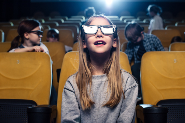 schattig kind in 3d bril kijken naar film in bioscoop samen met vrienden - Foto, afbeelding