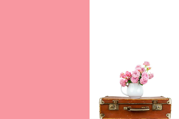 Vaaleanpunaisia kukkia kannussa vanhassa ruskeassa vintage-matkalaukussa. Ruusuja kannussa. Pinkit ruusut
. - Valokuva, kuva