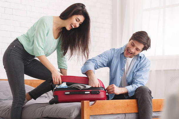 Couple trying to close full suitcase in bedroom - Photo, Image