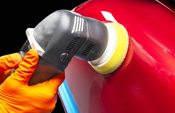 Car polish wax worker hands applying protective tape before polishing. Buffing and polishing car. Car detailing. Man holds a polisher in the hand and polishes the car - 写真・画像
