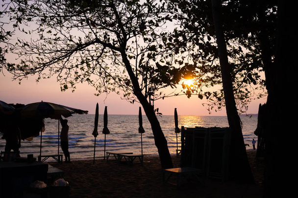 hermosa puesta de sol púrpura en la playa de Pattaya con una vista de las tumbonas y sombrillas a la sombra
. - Foto, imagen