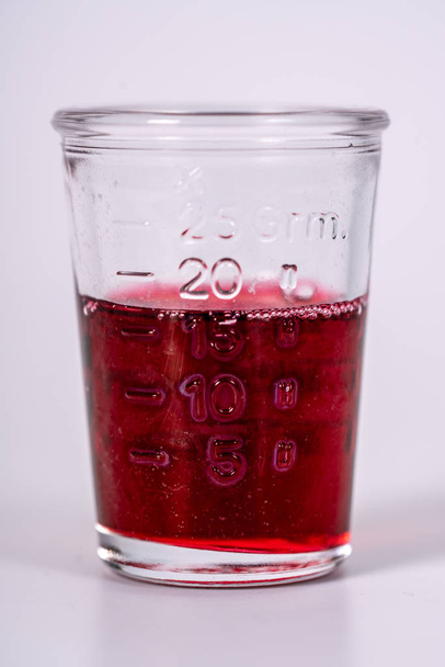 a glass filled with red medicine - Foto, afbeelding