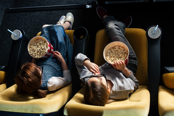 overhead view of friends eating popcorn and watching movie in cinema - Photo, Image