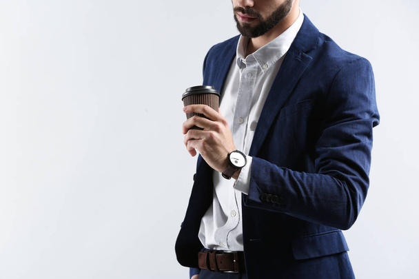 Fashionable young man drinking coffee on light background - Zdjęcie, obraz