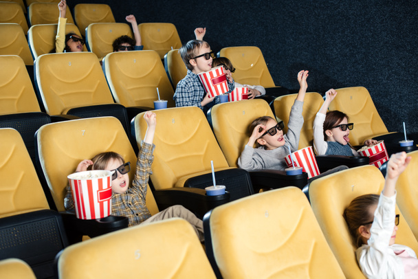 excited multicultural friends showing win gesture while watching movie together - Photo, Image
