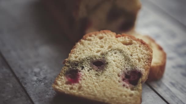 Footage of delicious sponge cake with cherry cut into pieces on wooden table.Tasty home baked biscuit dessert in close up.Enjoy natural pastry product for coffee break or lunch - Felvétel, videó