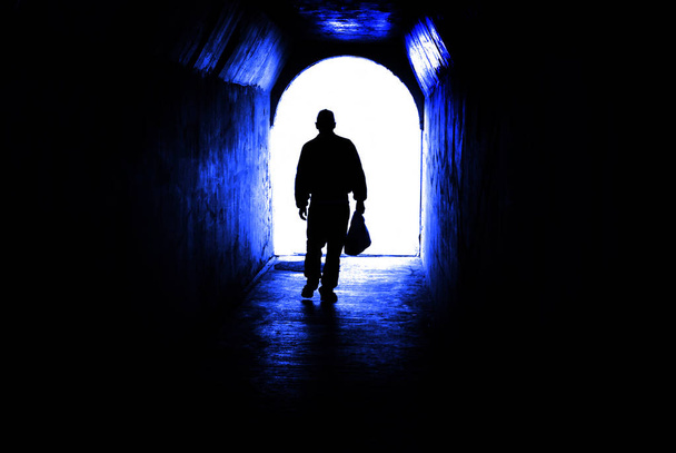 Persoon lopen via de tunnel naar licht aan einde. Accomplishin - Foto, afbeelding