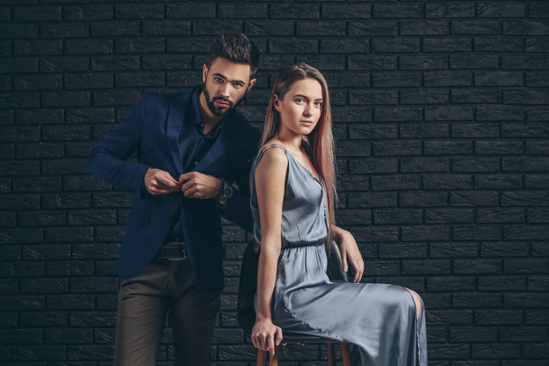 Fashionable young couple near dark brick wall - Фото, зображення