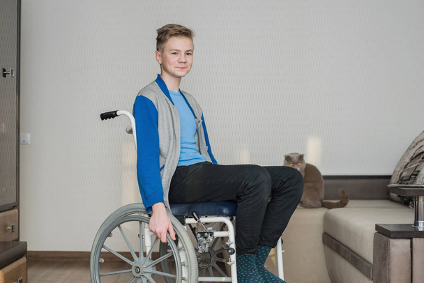 adolescente menino estudante sentado em uma cadeira de rodas em casa. - Foto, Imagem