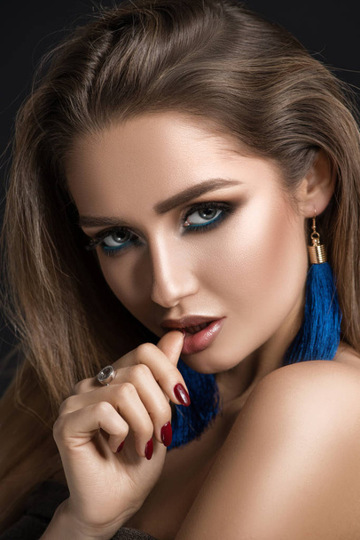 Brunette with eye makeup, in blue earrings. Portrait - Фото, зображення
