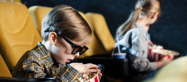 panoramic shot of cute boy in 3d glasses eating popcorn in cinema - Photo, Image