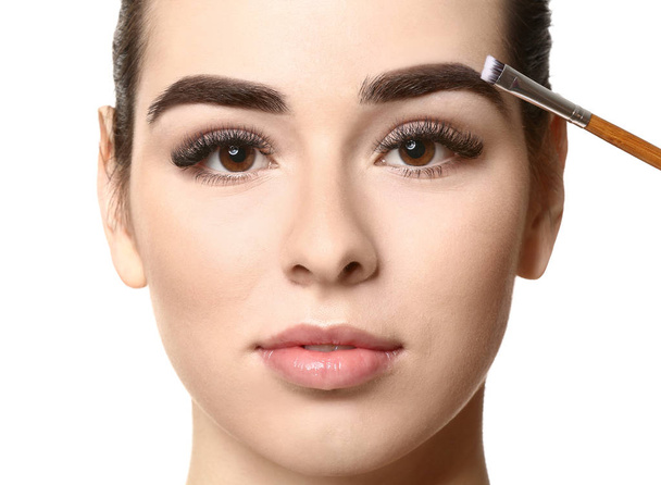 Young woman undergoing eyebrow correction procedure on white background - Foto, immagini