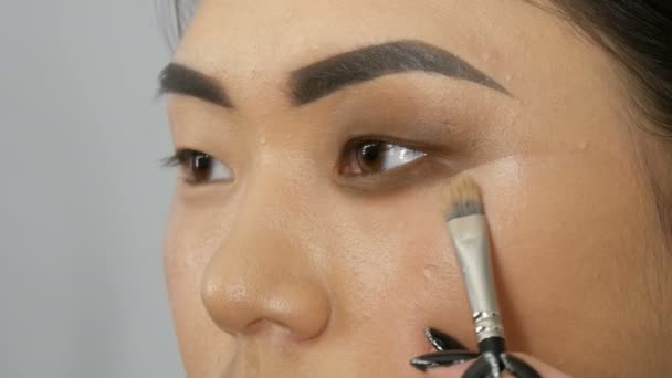 プロのスタイリスト メイクアップ アーティストは顔スタジオでアジアの少女モデル顔の煙のような目をします。 - 映像、動画