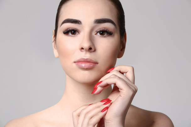 Young woman with beautiful eyebrows on grey background - Fotó, kép
