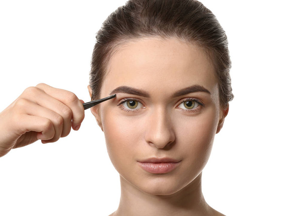 Young woman undergoing eyebrow correction procedure on white background - Fotografie, Obrázek