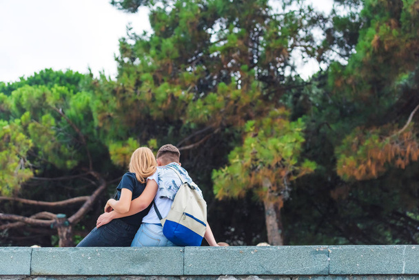 Пара влюбленных, сидящих на фоне сосновых растений. Мужчина и женщина отдыхают в парке. Роща хвойных деревьев
. - Фото, изображение