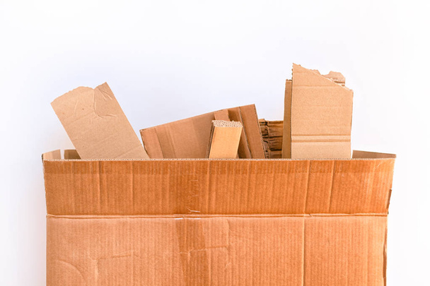 Cardboard box with cardboard pieces against white background.  - 写真・画像