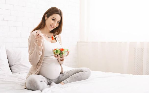 Gelukkige zwangere vrouw eten natuurlijke groente salade - Foto, afbeelding