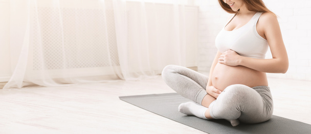 スポーツをした後の床に座ってアクティブ妊婦 - 写真・画像
