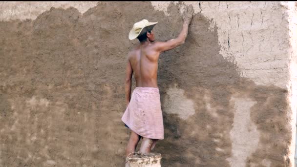 primo piano di un uomo coperto di fango su tutta la superficie di una stalla di tabacco per un nuovo uso. (Il fienile restaurato ) - Filmati, video