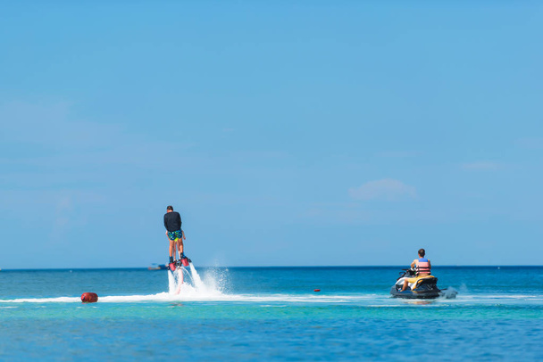 Su aşırı spor. Adam su flyboard uçuyor. Deniz aşırı dinleniyor. Su basıncı çok. Bir jet ski üzerinde yüzen kız - Fotoğraf, Görsel
