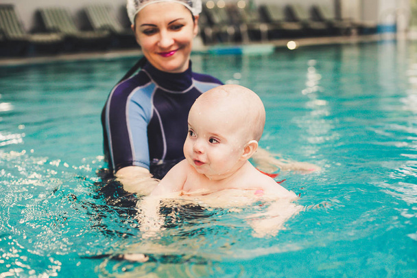 kleine jongen leren om te zwemmen in een zwembad - Foto, afbeelding