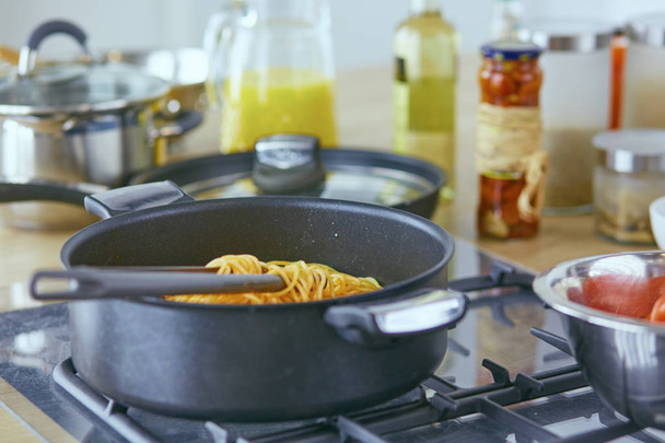 Pasta rolde op vork pan op het fornuis in de keuken - Foto, afbeelding