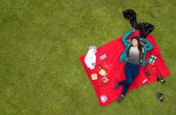 Gorgeous Latina student enjoying a picnic in the park, aerial view, available space for editing, ideal for blogs and ads - Photo, Image