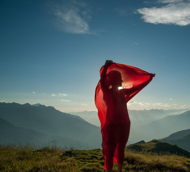 vrouw gewikkeld in een rode sjaal in de wind - Foto, afbeelding