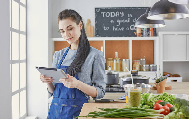 Happy woman looking recipe tablet kitchen reading cooking - Foto, imagen