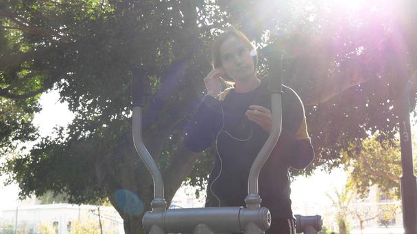 Preparing music for running at outdoor trainer machine - Photo, Image